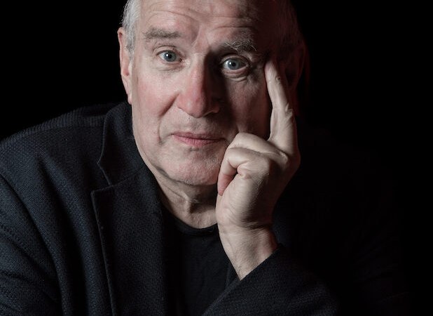 Ein &auml;lterer Mann in dunkler Kleidung st&uuml;tzt seinen Kopf mit der Hand und blickt nachdenklich in die Kamera vor schwarzem Hintergrund., &copy; Renitenztheater Stuttgart e.V.