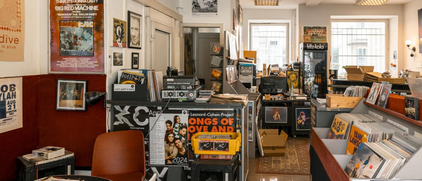 A cozy record store with vinyls, posters and music magazines. In the background, a fridge with drinks and a desk with a computer., © SMG, Sarah Schmid
