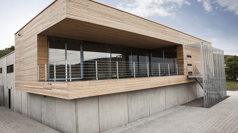 Modern building with wooden cladding, large windows and metal railings. Exterior view in daylight, clear lines and minimalist design., &copy; Weingut Knau&szlig;