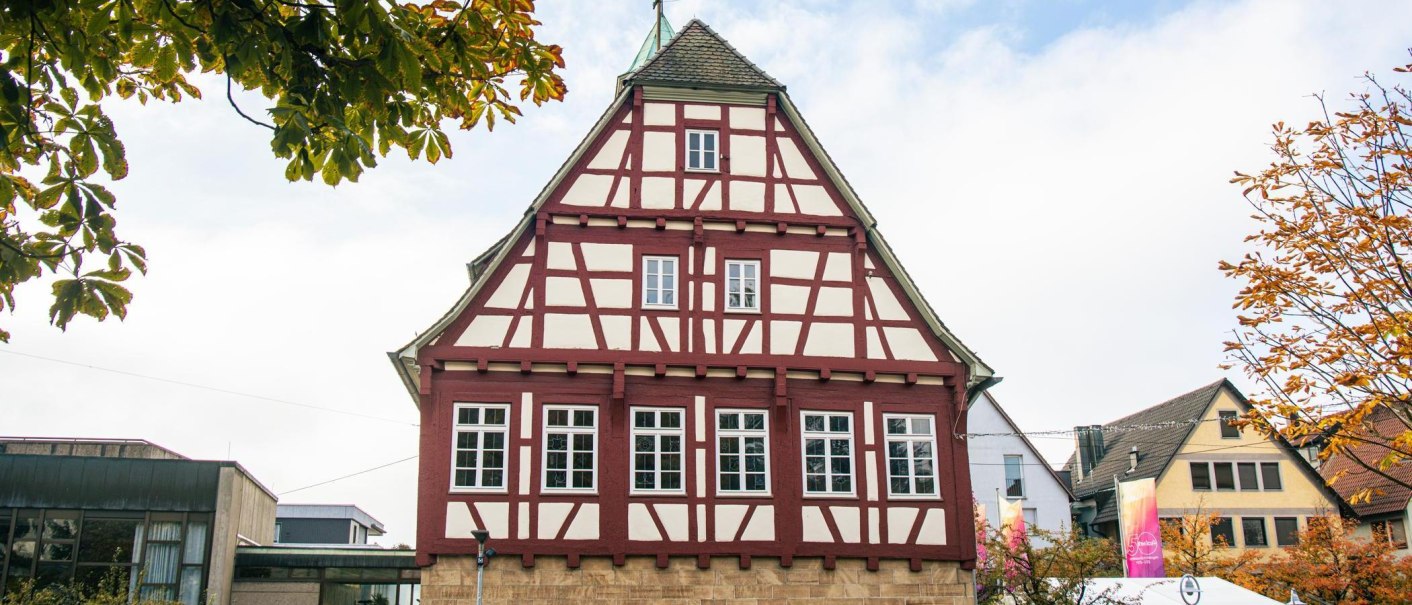A traditional half-timbered house in the center of Echterdingen, surrounded by autumnal trees and modern architecture., © Stuttgart-Marketing GmbH, Sarah Schmid
