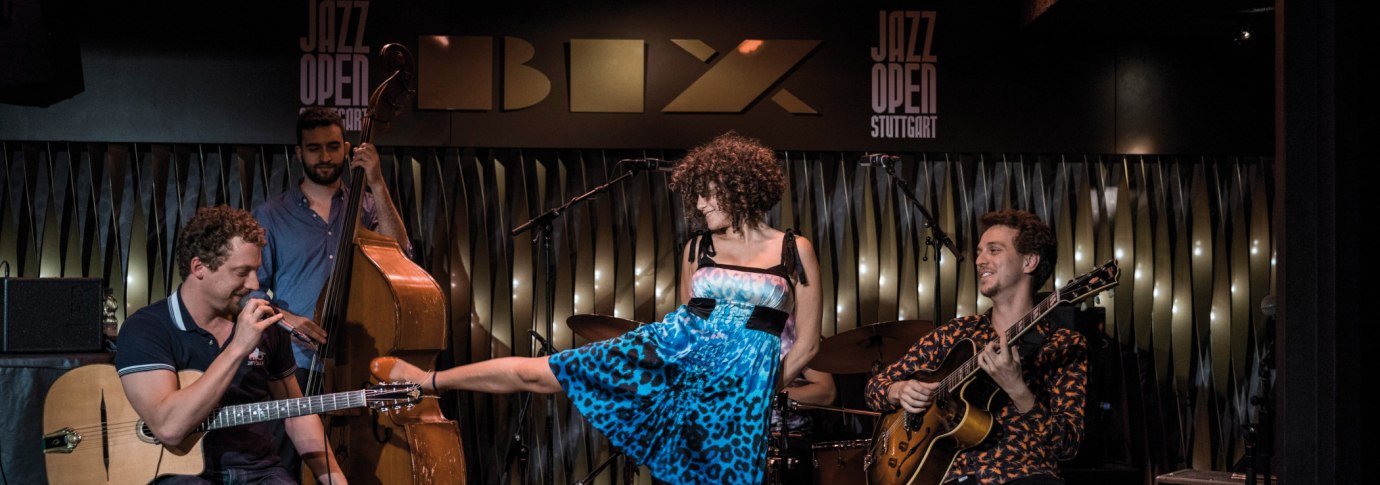 Eine Band spielt im BIX Jazzclub. Ein Gitarrist, ein Kontrabassist und eine S&auml;ngerin in blauem Kleid sind zu sehen. "Jazz Open Stuttgart" im Hintergrund., &copy; Peter Steinheisser