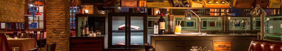 Stylish restaurant with brick walls, laid tables and bottles of wine. Warm light creates a cozy atmosphere., © ©Pier 51