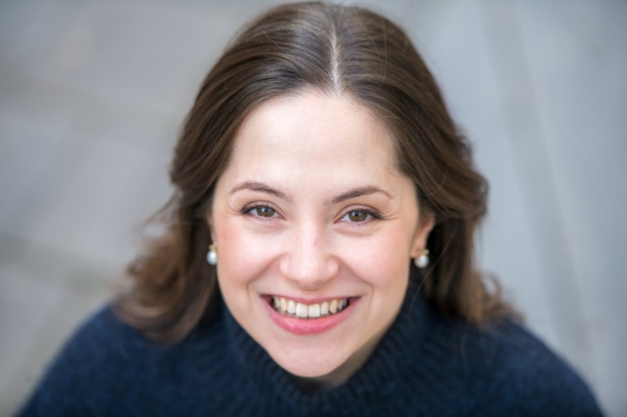 Nahaufnahme einer lächelnden Frau mit braunen Haaren und Perlenohrringen, die in die Kamera schaut., © Giorgia Cappello