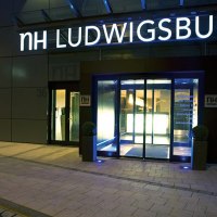 Eingang des NH Hotels in Ludwigsburg bei Nacht, beleuchtet mit blauem Licht. Der Schriftzug 'NH LUDWIGSBURG' ist gut sichtbar., &copy; NH Ludwigsburg