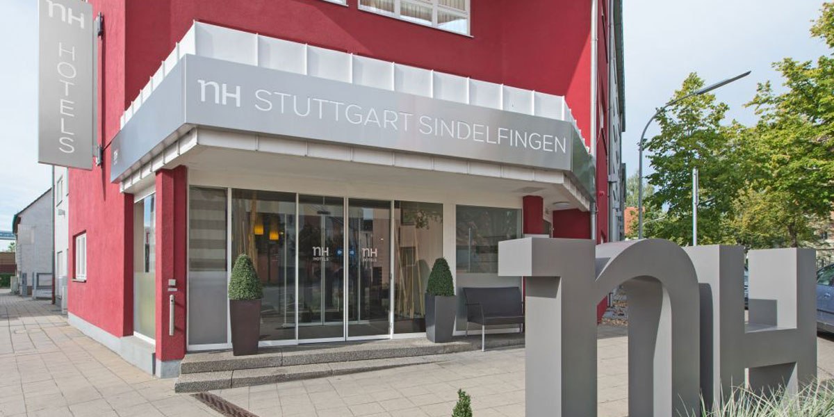 Eingang des NH Hotels in Sindelfingen mit roter Fassade, großem Logo und Pflanzen vor der Tür., © NH Stuttgart Sindelfingen Eingang des NH Hotels in Sindelfingen mit roter Fassade, großem Logo und Pflanzen vor der Tür., © NH Stuttgart Sindelfingen