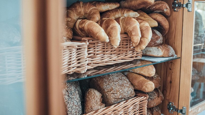 Ein Regal mit Körben voller Croissants und Brote in einem Holzschrank., © Raupe Immersatt e.V., Stuttgart