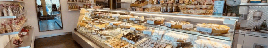 A cozy café with a display case full of pastries and chocolate. Decorative figurines and a chandelier complete the ambience., © FreCla Gastronomiebetriebe GmbH