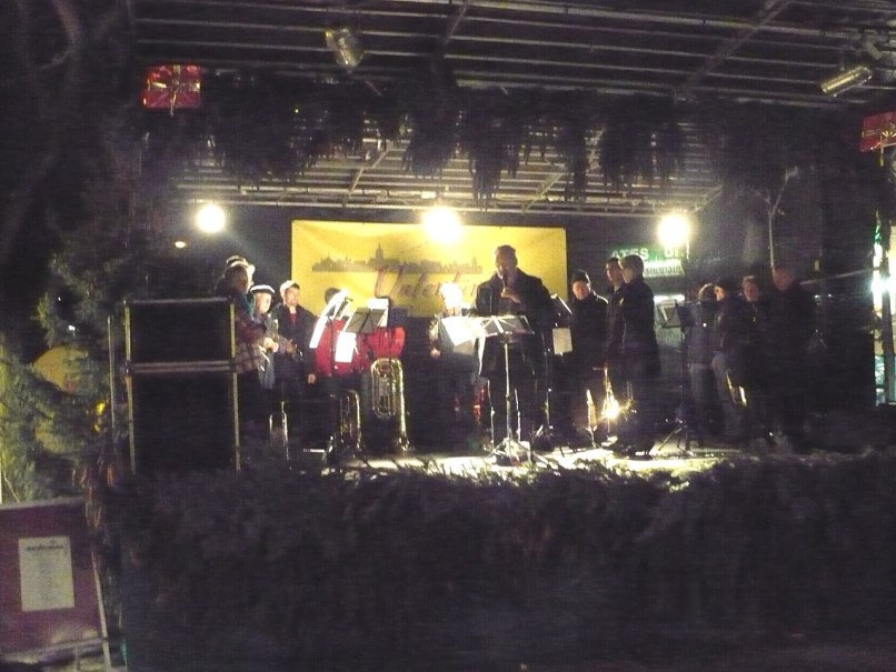 Eine Musikgruppe spielt auf einer festlich dekorierten Bühne in Untertürkheim. Die Bühne ist mit Lichtern und Tannenzweigen geschmückt., © Foto: Enslin