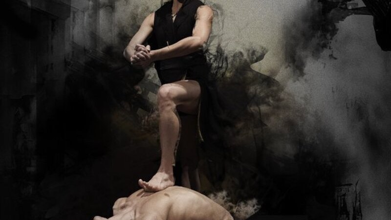 Zwei Tänzer in einer dramatischen Pose: Eine Person steht auf der Brust einer liegenden Person, umgeben von dunklem Rauch., © Theaterhaus Stuttgart e.V.