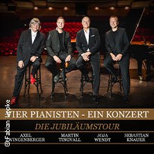Vier M&auml;nner sitzen auf Hockern vor einem Fl&uuml;gel in einem leeren Konzertsaal. Der Titel "Vier Pianisten - Ein Konzert - Die Jubil&auml;umstour" ist eingeblendet., &copy; links im Bild