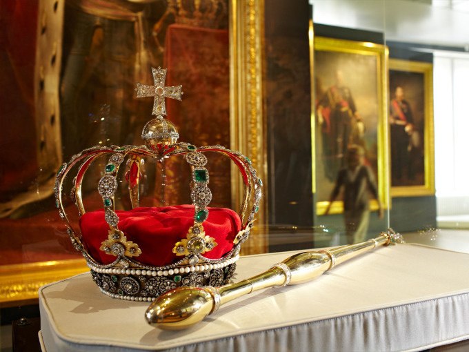A richly decorated crown and sceptre on a pedestal in a museum, surrounded by paintings., &copy; Landesmuseum W&uuml;rttemberg