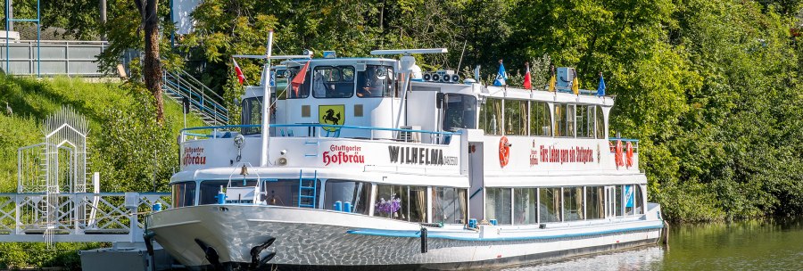 Das Passagierschiff MS Wilhelma liegt an einem gr&uuml;nen Flussufer vor Anker, umgeben von B&auml;umen., &copy; all copyrights are reserved by maks richter