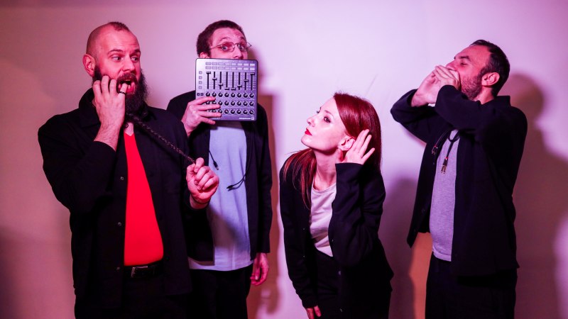 Vier Personen in einer humorvollen Szene: eine h&auml;lt ein Audioger&auml;t, eine andere tut so, als ob sie zuh&ouml;rt, w&auml;hrend die anderen Grimassen schneiden., &copy; Aaron Giordani