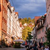 Straßenszene im Bohnenviertel mit historischen Gebäuden, Menschen in Straßencafés und grünem Laub. Die Abendsonne beleuchtet die Fassaden., © SMG Thomas Niedermüller Straßenszene im Bohnenviertel mit historischen Gebäuden, Menschen in Straßencafés und grünem Laub. Die Abendsonne beleuchtet die Fassaden., © SMG Thomas Niedermüller