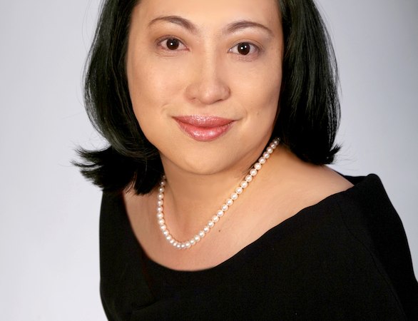 Frau mit schwarzem Haar und Perlenkette, lächelnd vor grauem Hintergrund., © Fortepiano-Festival Stuttgart