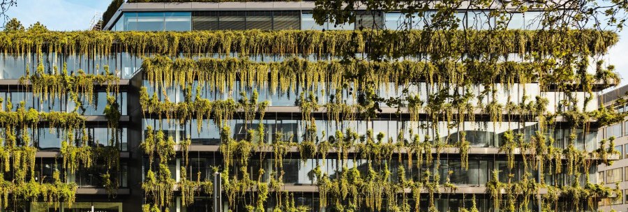 Ein modernes Geb&auml;ude mit einer &uuml;ppig begr&uuml;nten Fassade und gro&szlig;en Glasfenstern. Pflanzen h&auml;ngen von den Etagen herab., &copy; Stuttgart-Marketing GmbH, Sarah Schmid