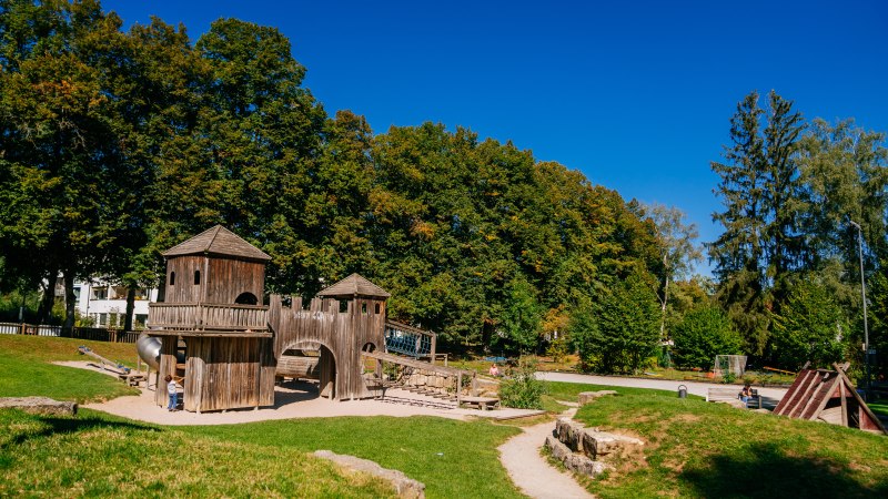 Spielplatz mit Holzkonstruktionen im Stadtpark Welzheim, umgeben von grünen Bäumen und blauem Himmel., © Stuttgart-Marketing GmbH, Thomas Niedermüller