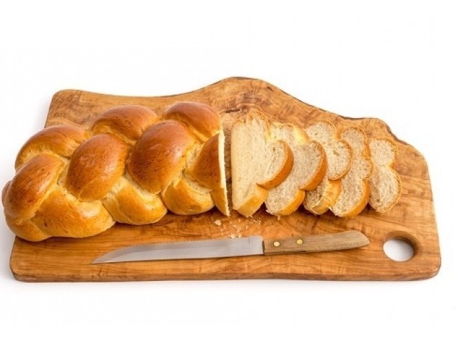 A yeast plait lies on a wooden board, partially sliced. A knife lies next to it., © Cool-Tours StattReisen A yeast plait lies on a wooden board, partially sliced. A knife lies next to it., © Cool-Tours StattReisen