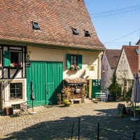 An idyllic courtyard in Nürtingen's old town with a half-timbered house, green shutters and cozy seating under a tree., © Stuttgart-Marketing GmbH, Sarah Schmid An idyllic courtyard in Nürtingen's old town with a half-timbered house, green shutters and cozy seating under a tree., © Stuttgart-Marketing GmbH, Sarah Schmid