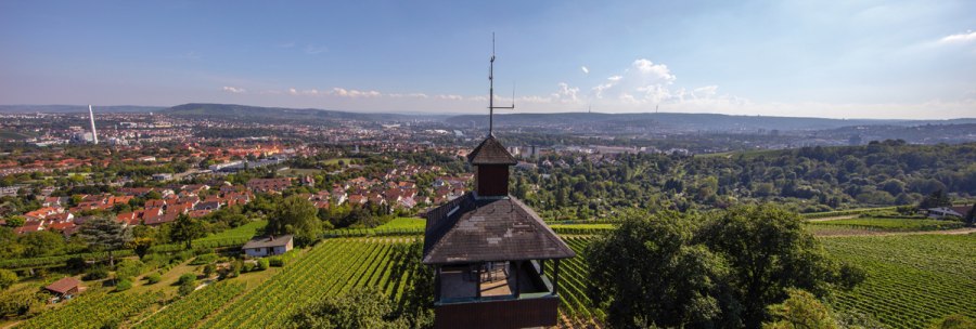 Burgholzhof observation tower in Stuttgart, surrounded by vineyards, with a view of the city and hills in the background under a clear sky., © Stuttgart-Marketing GmbH Burgholzhof observation tower in Stuttgart, surrounded by vineyards, with a view of the city and hills in the background under a clear sky., © Stuttgart-Marketing GmbH