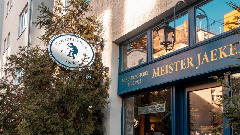 Entrance to the Meister Jaekel shoemaker's shop with a sign indicating the year it was founded, 1932. Surrounded by green plants., &copy; SMG Stuttgart Marketing GmbH - Sarah Schmid