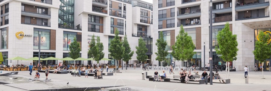 The Milaneo shopping center on Mail&auml;nder Platz with modern buildings, trees and a fountain in the foreground. People sit and walk., &copy; Peter Oppenl&auml;nder