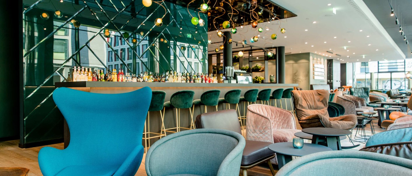 Modern lobby with elegant armchairs, bar stools and a bar in the background. Decorative lighting and stylish furnishings., &copy; Motel One - Stuttgart Hauptbahnhof
