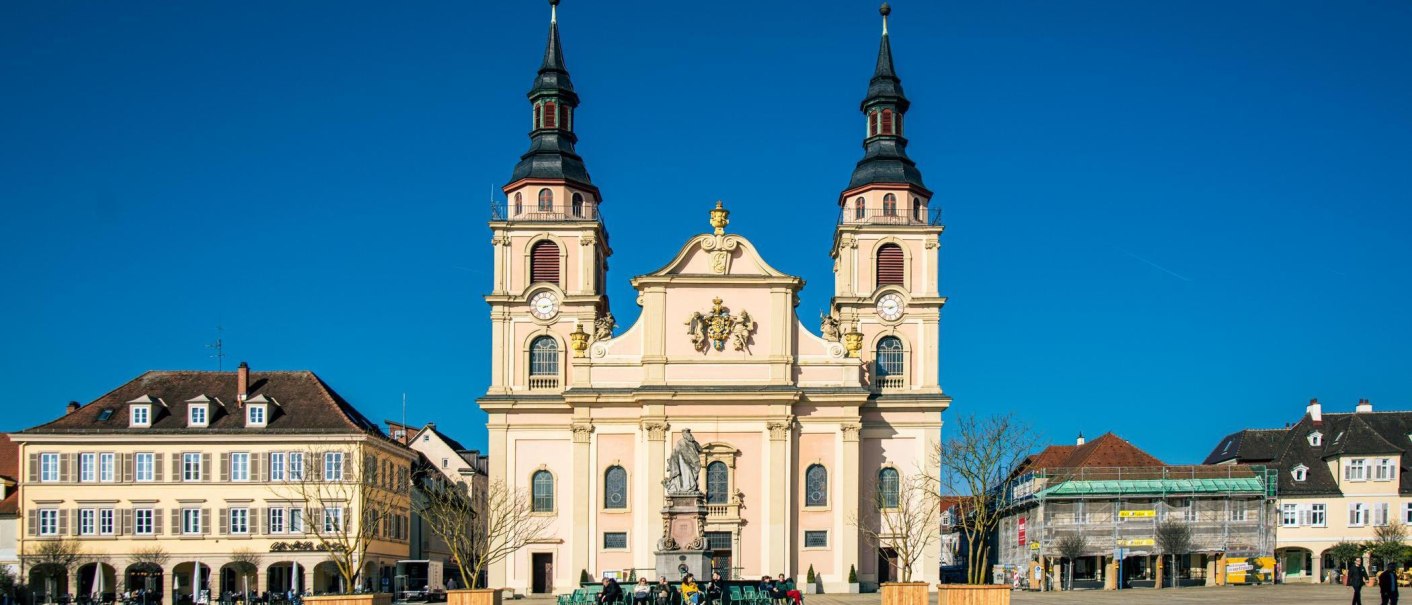 The market square in Ludwigsburg shows a magnificent church with two towers, surrounded by historic buildings under a bright blue sky., © Stuttgart-Marketing GmbH, Sarah Schmid