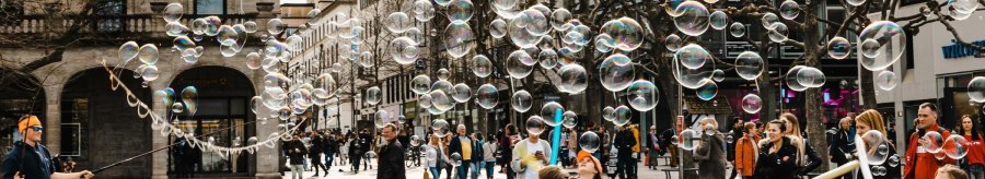 A street artist creates soap bubbles on a busy street. Children play enthusiastically with the bubbles while passers-by look on., &copy; Stuttgart-Marketing GmbH, Sarah Schmid