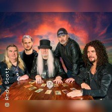 Bandmitglieder von The Sweet sitzen an einem Tisch mit Tarotkarten vor einem dramatischen Himmel., © links im Bild Bandmitglieder von The Sweet sitzen an einem Tisch mit Tarotkarten vor einem dramatischen Himmel., © links im Bild