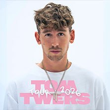 Ein junger Mann mit lockigem Haar tr&auml;gt ein wei&szlig;es T-Shirt mit der Aufschrift 'Tom Twers Tour 2026'., &copy; links im Bild