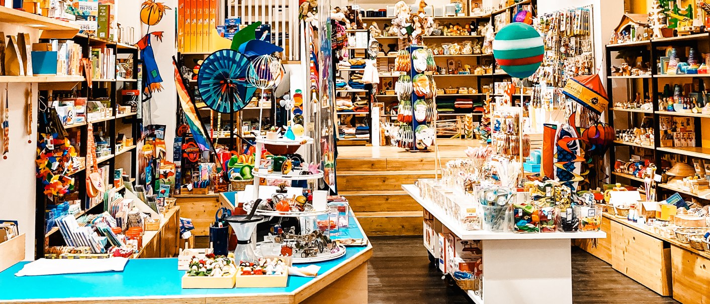 Colorful toy store with shelves full of toys and hanging decorations. Cheerful atmosphere with lots of colors and different toys., © 1000schön