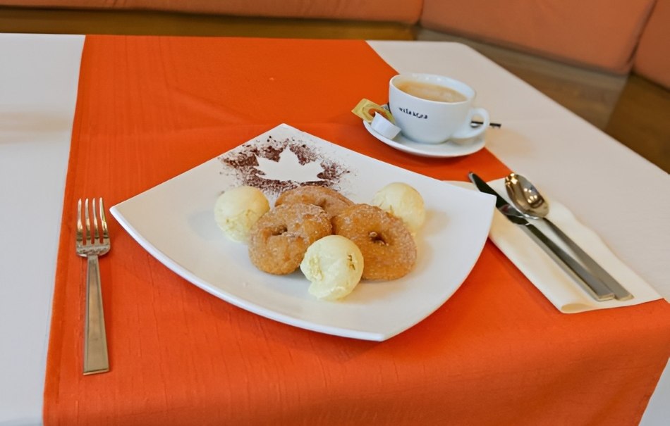 Plate with donuts and ice cream on a red tablecloth, coffee and cutlery next to it., © Hotel Neuwirtshaus Plate with donuts and ice cream on a red tablecloth, coffee and cutlery next to it., © Hotel Neuwirtshaus