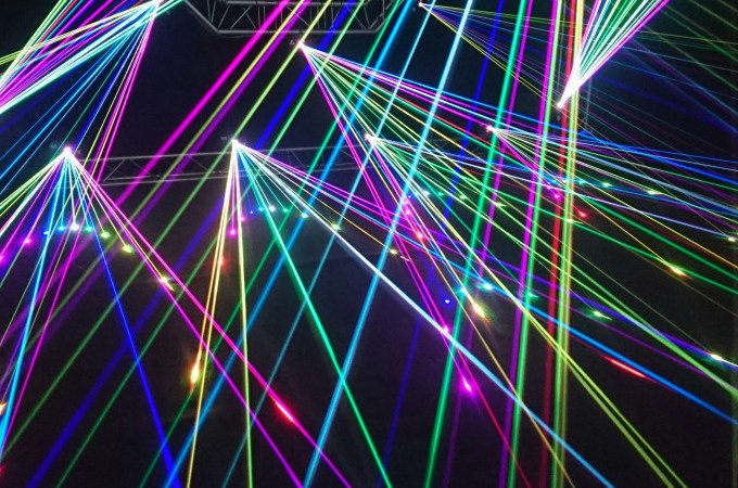 Bunte Laserstrahlen durchziehen einen dunklen Raum und erzeugen ein lebendiges, futuristisches Muster., &copy; Cool-Tours StattReisen