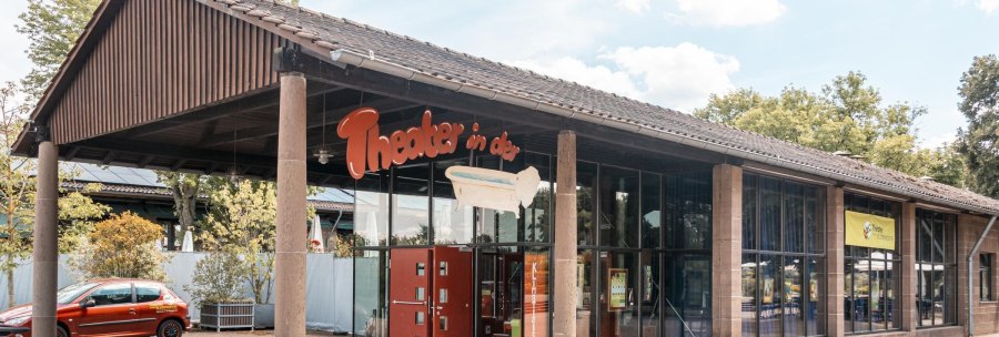 Entrance of the theater in the bathtub with glass front and red car in front of it. A sign with the name of the theater and a bathtub is visible., &copy; SMG Stuttgart Marketing GmbH - Sarah Schmid