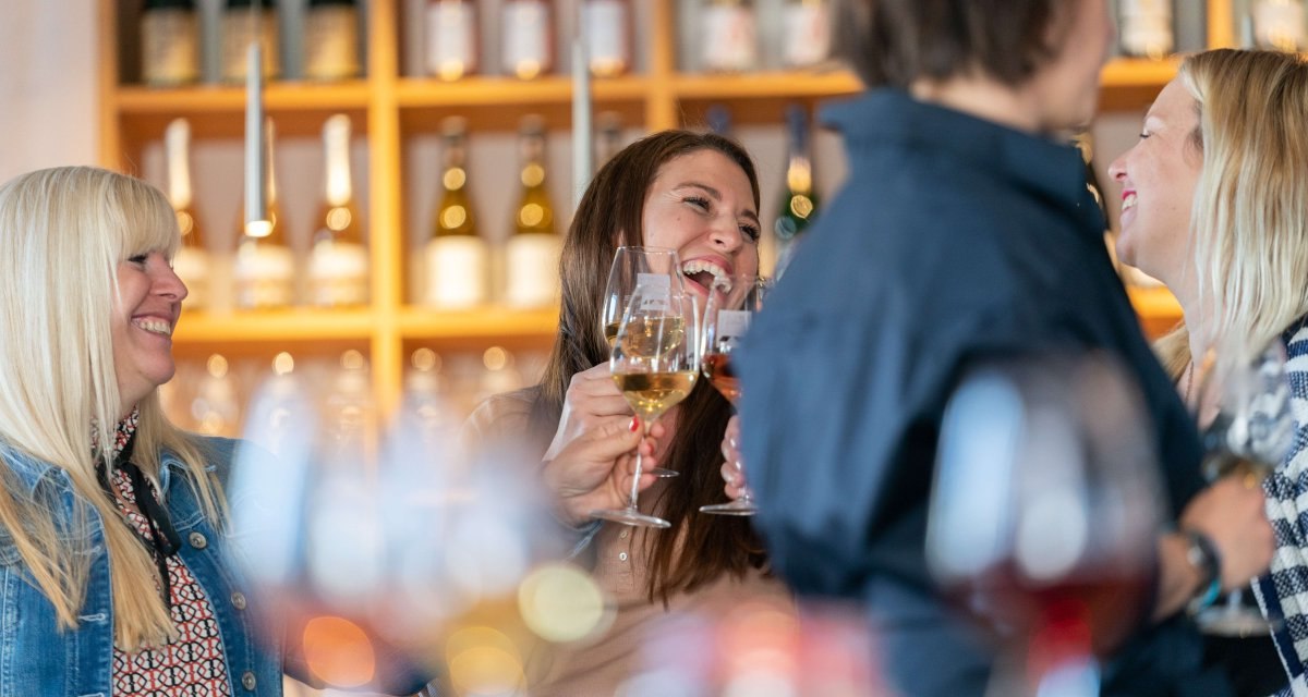 Eine Gruppe von Menschen stößt mit Weingläsern in einer Vinothek an. Im Hintergrund sind Weinflaschen in Regalen zu sehen., © Stuttgart-Marketing GmbH, Thomas Niedermüller Eine Gruppe von Menschen stößt mit Weingläsern in einer Vinothek an. Im Hintergrund sind Weinflaschen in Regalen zu sehen., © Stuttgart-Marketing GmbH, Thomas Niedermüller