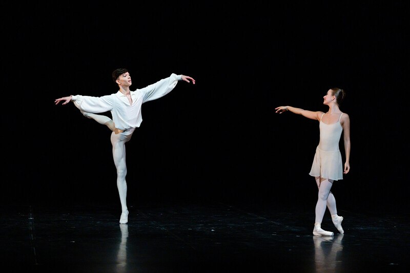 Zwei Ballettt&auml;nzer auf der B&uuml;hne, einer in wei&szlig;em Hemd und der andere in einem cremefarbenen Kleid, f&uuml;hren eine elegante Pose aus., &copy; W&uuml;rttembergische Staatstheater Stuttgart