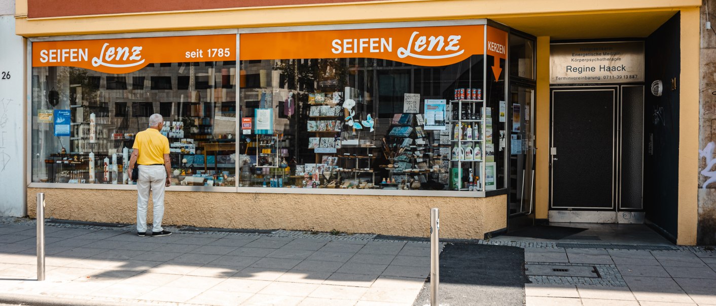 Ein Mann betrachtet das Schaufenster des Geschäfts 'Seifen Lenz', das seit 1785 besteht. Das Gebäude hat eine orangefarbene Markise., © SMG Stuttgart Marketing GmbH - Sarah Schmid