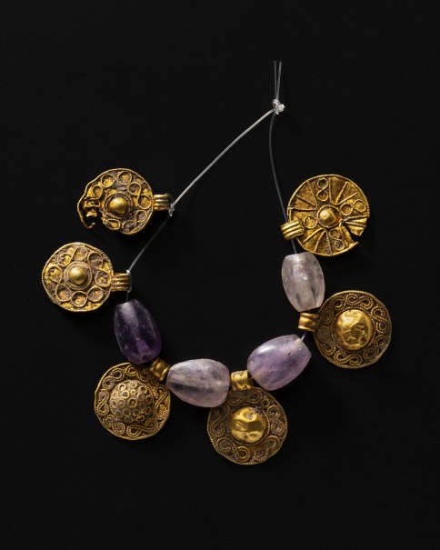 Halskette mit goldenen, verzierten Anhängern und violetten Steinen auf schwarzem Hintergrund., © Landesmuseum Württemberg, Hendrik Zwietasch