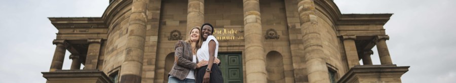 Two people embrace with a smile in front of the imposing façade of the Stuttgart burial chapel with its columns., © Stuttgart-Marketing GmbH, wpsteinheisser Two people embrace with a smile in front of the imposing façade of the Stuttgart burial chapel with its columns., © Stuttgart-Marketing GmbH, wpsteinheisser