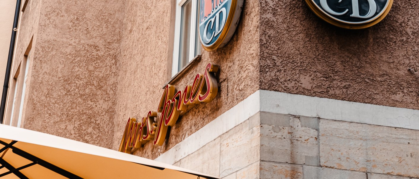 Gebäudefassade mit 'Mrs. Jones'-Schriftzug und Wappen 'CD' über einem Straßenschild 'Geißstr.'., © SMG Stuttgart Marketing GmbH - Sarah Schmid