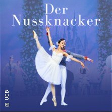Ballettszene aus "Der Nussknacker" mit Tänzerin in weißem Kleid, Tänzer im Hintergrund, blauer Hintergrund mit Schloss und Bäumen., © links im Bild Ballettszene aus "Der Nussknacker" mit Tänzerin in weißem Kleid, Tänzer im Hintergrund, blauer Hintergrund mit Schloss und Bäumen., © links im Bild