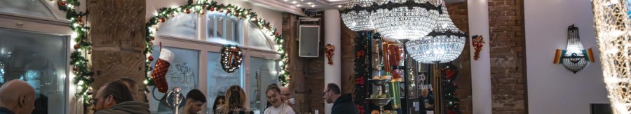 Festively decorated bar with chandeliers, guests at the bar and Christmas decorations. Glasses and bottles on the bar., © SMG Stuttgart Marketing GmbH - Sarah Schmid