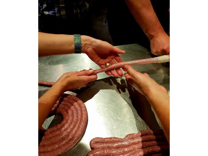 People's hands fill sausage mixture into casings on a metal table. The scene takes place in a cooking class., © Kultweine-Kochwelten-Kunstücke - Kochschule Sonja Lenz People's hands fill sausage mixture into casings on a metal table. The scene takes place in a cooking class., © Kultweine-Kochwelten-Kunstücke - Kochschule Sonja Lenz