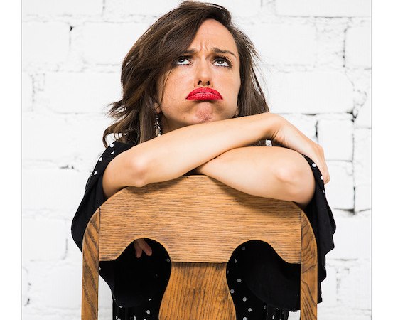 Frau mit rotem Lippenstift lehnt sich nachdenklich auf einen Holzstuhl vor einer weißen Ziegelwand., © Renitenztheater Stuttgart e.V. Frau mit rotem Lippenstift lehnt sich nachdenklich auf einen Holzstuhl vor einer weißen Ziegelwand., © Renitenztheater Stuttgart e.V.