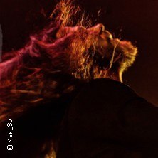 Person mit langen, wehenden Haaren in rotem Licht, dynamische Bewegung, Konzertatmosphäre., © links im Bild Person mit langen, wehenden Haaren in rotem Licht, dynamische Bewegung, Konzertatmosphäre., © links im Bild