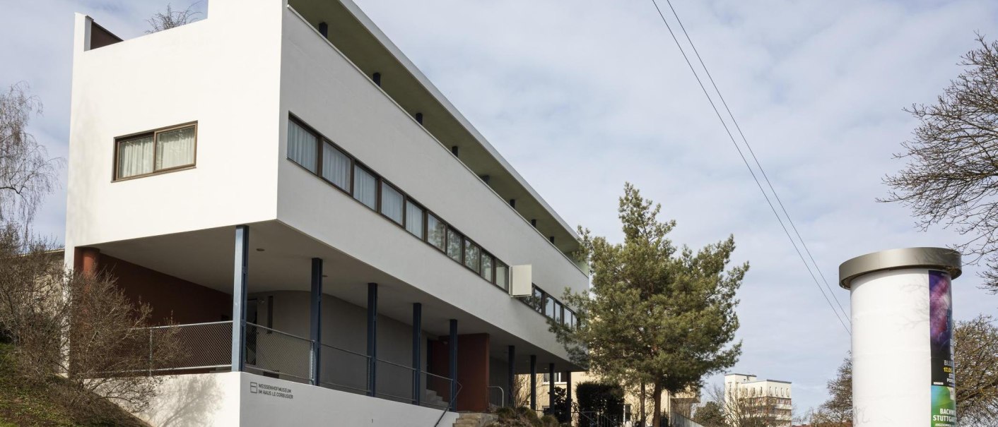 Modern building with a white façade and large windows, surrounded by trees and a billboard., © SMG Stuttgart Marketing GmbH - Sarah Schmid Modern building with a white façade and large windows, surrounded by trees and a billboard., © SMG Stuttgart Marketing GmbH - Sarah Schmid