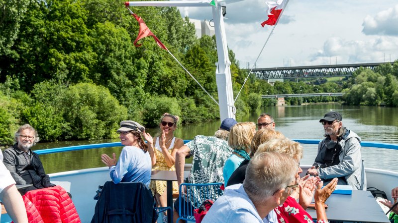 People enjoying a boat trip on the Neckar. They are sitting on the deck, surrounded by green countryside and chatting happily., © all copyrights are reserved by maks richter People enjoying a boat trip on the Neckar. They are sitting on the deck, surrounded by green countryside and chatting happily., © all copyrights are reserved by maks richter