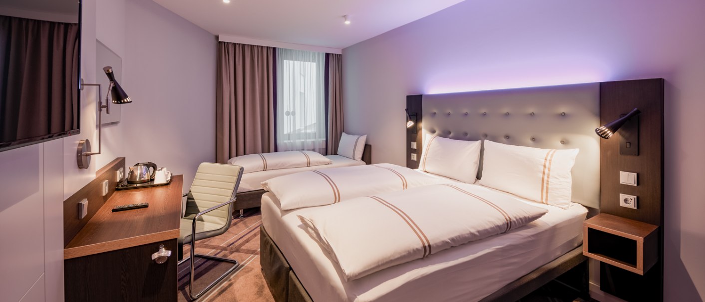 Modernes Dreibettzimmer mit zwei Einzelbetten, Schreibtisch, Fernseher und stilvoller Beleuchtung. Helle Farben und gemütliche Atmosphäre., © Premier Inn Modernes Dreibettzimmer mit zwei Einzelbetten, Schreibtisch, Fernseher und stilvoller Beleuchtung. Helle Farben und gemütliche Atmosphäre., © Premier Inn