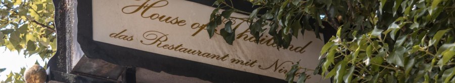 Ein Schild mit der Aufschrift 'House of Thailand, das Restaurant mit Niveau', umgeben von gr&uuml;nen Bl&auml;ttern., &copy; Stuttgart Marketing GmbH, Sarah Schmid